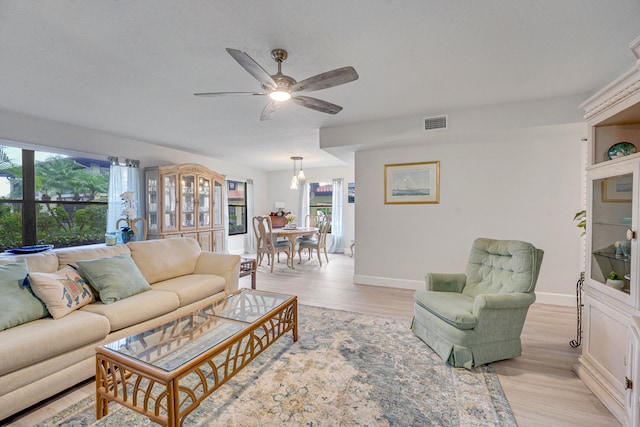 living room featuring light hardwood / wood-style flooring and ceiling fan with notable chandelier