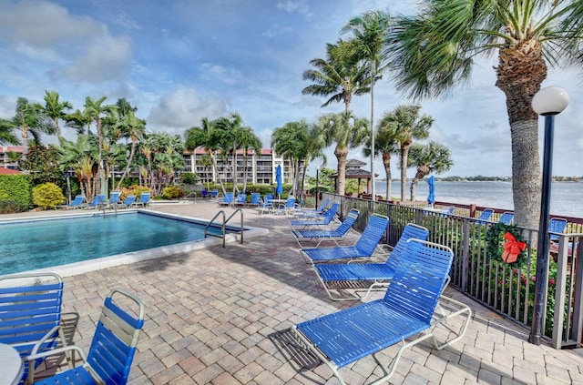 view of swimming pool featuring a water view and a patio area