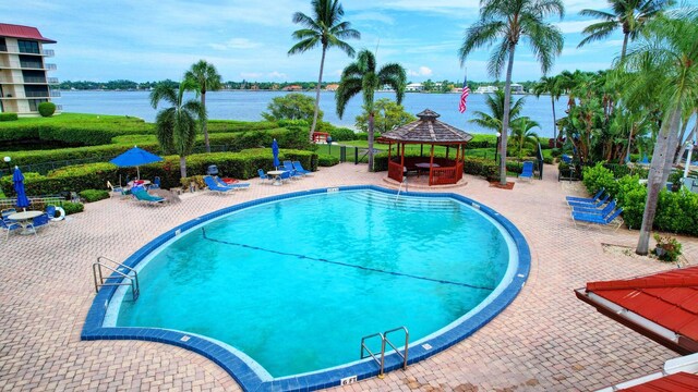 view of swimming pool featuring a water view, a patio area, and a gazebo