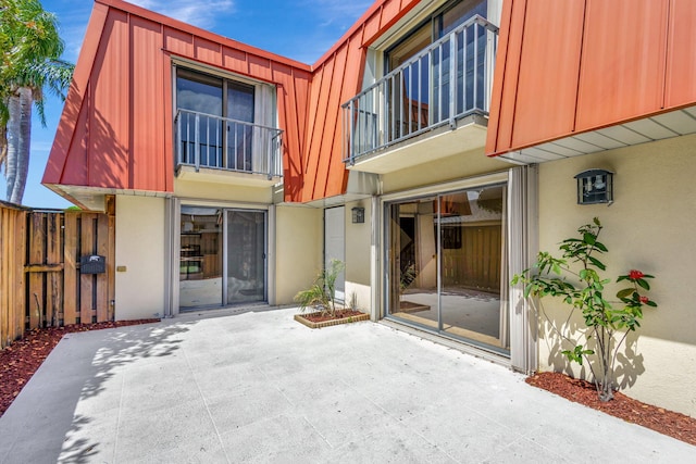 exterior space featuring mansard roof, a patio area, fence, and stucco siding