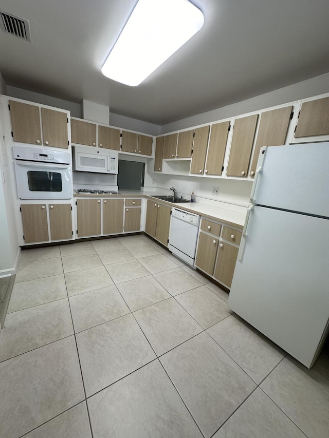 kitchen with light tile patterned floors, white appliances, and sink