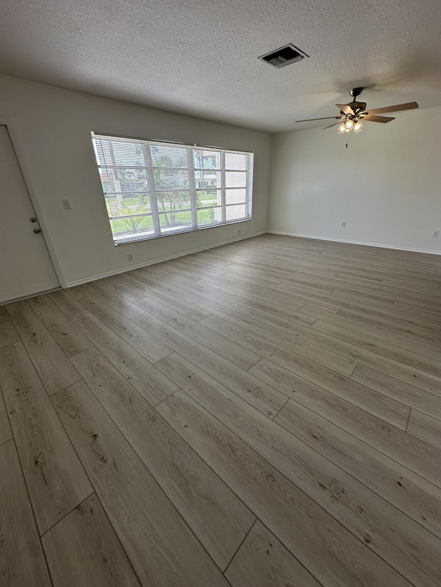 unfurnished room with ceiling fan, light hardwood / wood-style flooring, and a textured ceiling