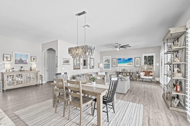 dining space featuring ceiling fan with notable chandelier and hardwood / wood-style flooring