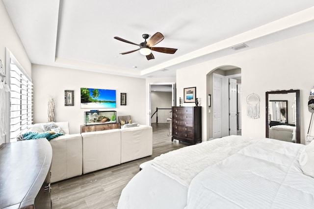 bedroom featuring ceiling fan, light hardwood / wood-style floors, and a raised ceiling