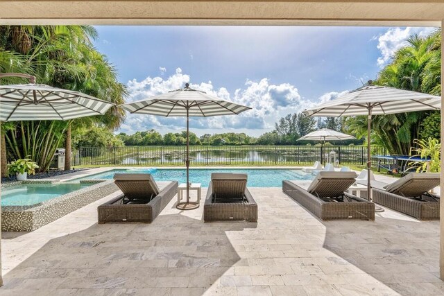 view of pool featuring pool water feature, a hot tub, a water view, and a patio