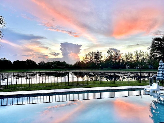 pool at dusk featuring a water view