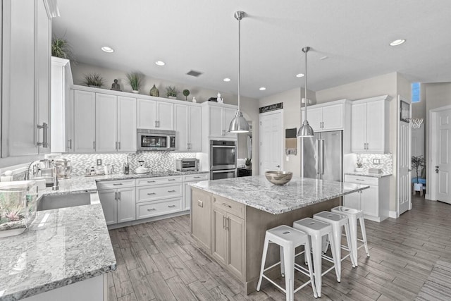 kitchen featuring stainless steel appliances, a kitchen island, backsplash, white cabinets, and sink