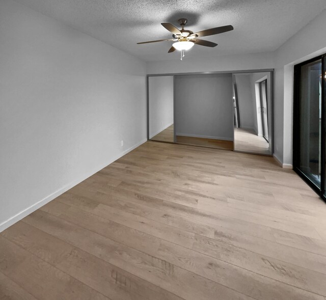 spare room with ceiling fan, light wood-type flooring, and a textured ceiling