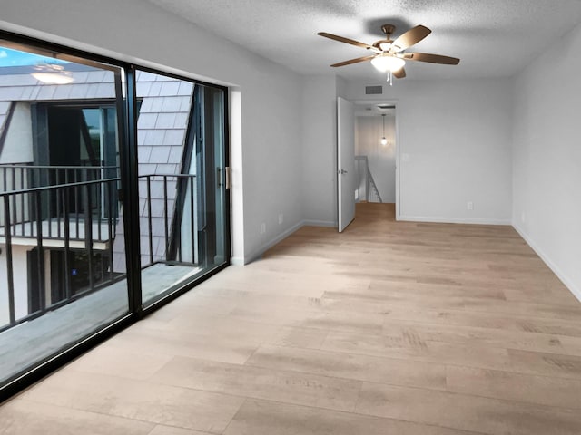 empty room featuring ceiling fan, light hardwood / wood-style floors, and a textured ceiling