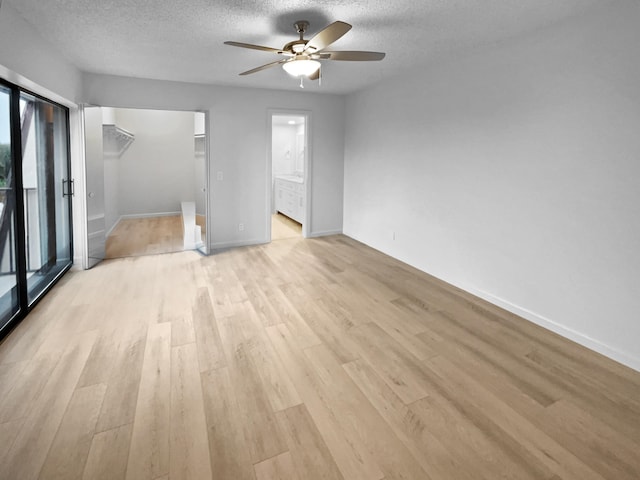 unfurnished room featuring a textured ceiling, ceiling fan, light wood-type flooring, and plenty of natural light