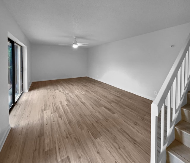 spare room featuring a healthy amount of sunlight, ceiling fan, wood-type flooring, and a textured ceiling