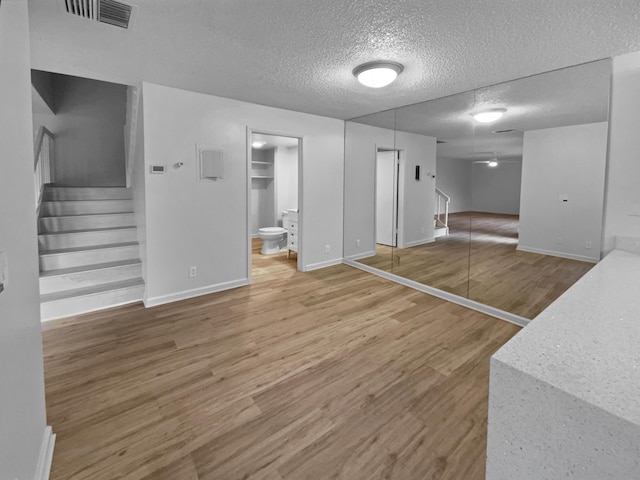 basement with ceiling fan, hardwood / wood-style floors, and a textured ceiling