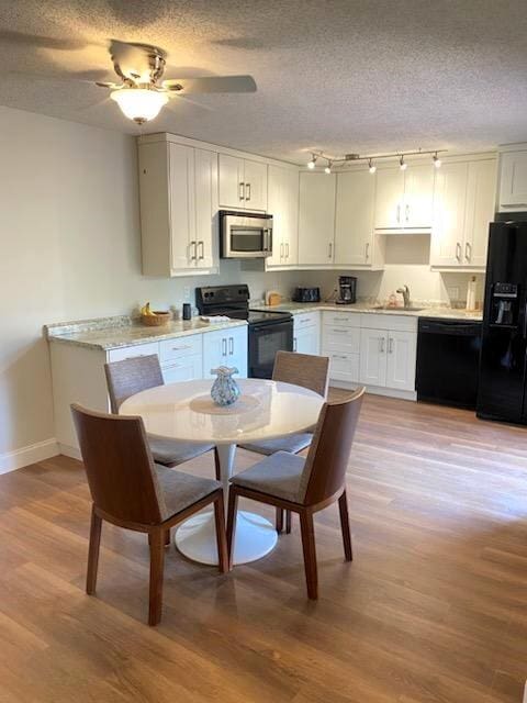 dining space with a textured ceiling, light hardwood / wood-style flooring, sink, and ceiling fan