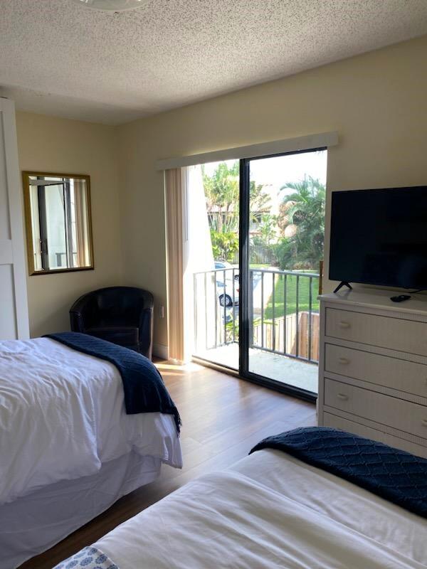 bedroom featuring access to outside, hardwood / wood-style floors, and a textured ceiling