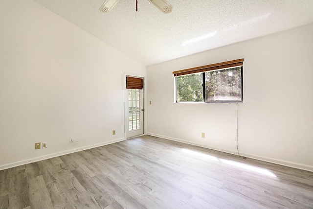 spare room featuring vaulted ceiling, a textured ceiling, and light hardwood / wood-style floors