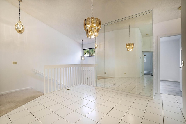 tiled spare room featuring an inviting chandelier