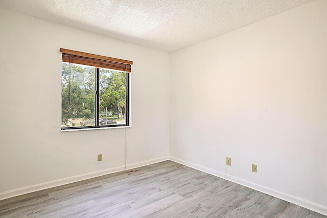 empty room with light hardwood / wood-style flooring and a textured ceiling