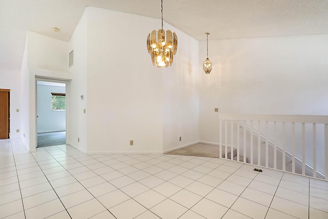 empty room with an inviting chandelier, a towering ceiling, and light tile patterned floors