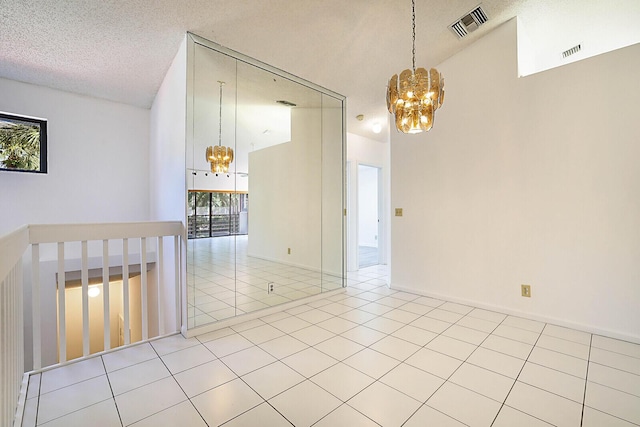 unfurnished room with high vaulted ceiling, light tile patterned floors, a notable chandelier, and a textured ceiling