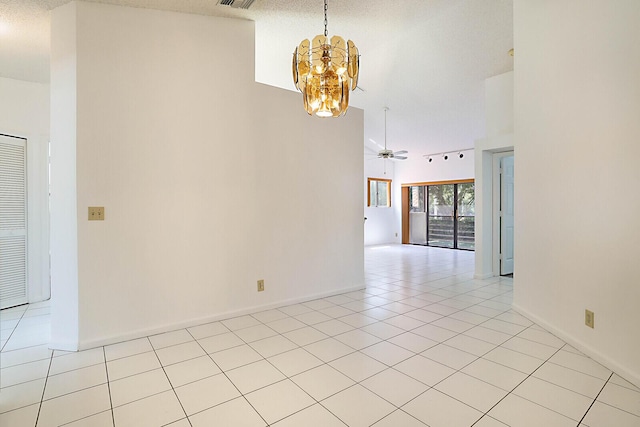 empty room with light tile patterned flooring, a towering ceiling, and ceiling fan with notable chandelier