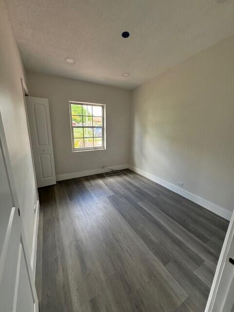 unfurnished room featuring dark hardwood / wood-style flooring and a textured ceiling