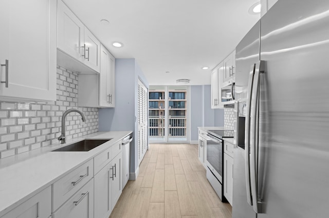 kitchen featuring appliances with stainless steel finishes, sink, decorative backsplash, and white cabinetry