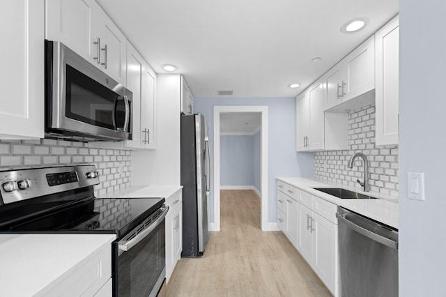 kitchen with stainless steel appliances, white cabinets, light countertops, and a sink