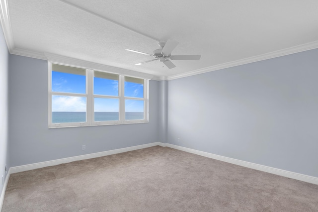 spare room with light colored carpet, a water view, a ceiling fan, baseboards, and ornamental molding