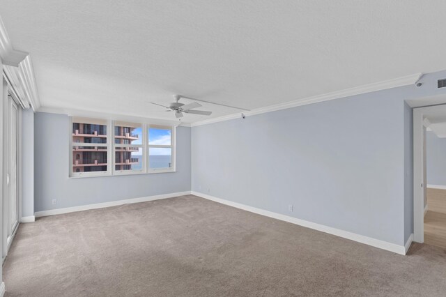 carpeted spare room featuring ceiling fan, a textured ceiling, and crown molding