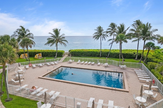 pool featuring a water view, fence, a lawn, and a patio