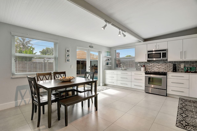 kitchen featuring light tile patterned flooring, a wealth of natural light, white cabinets, track lighting, and appliances with stainless steel finishes