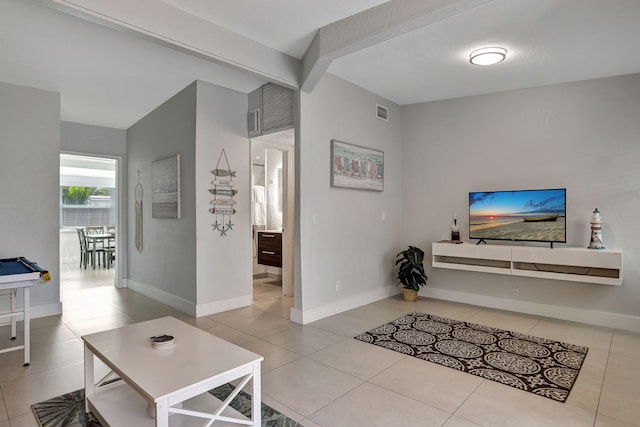 living room featuring beam ceiling and light tile patterned floors