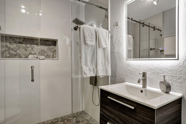 bathroom featuring vanity, a shower with door, and toilet