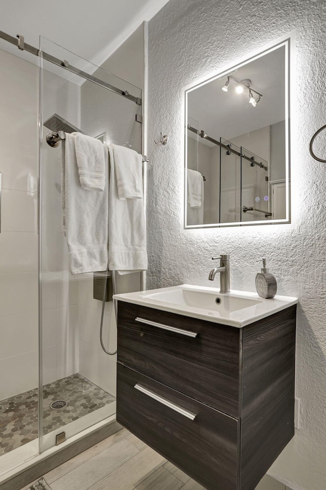5278 NE 19th Ter, Pompano Beach, FL 33064 - full bath featuring a textured wall, a stall shower, vanity, and wood finished floors