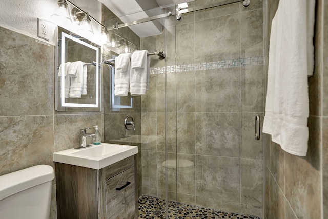 bathroom featuring vanity, walk in shower, tile walls, and toilet