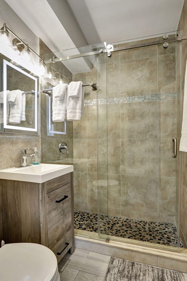 bathroom with vanity, walk in shower, tile walls, and toilet