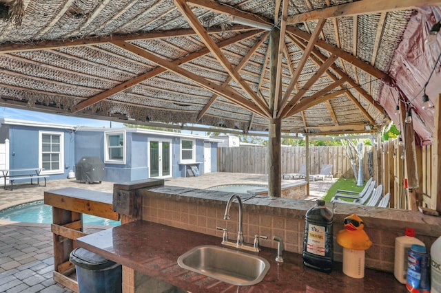 view of patio featuring sink, a gazebo, a grill, and a fenced in pool