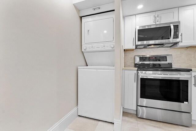 kitchen featuring stacked washer / dryer, appliances with stainless steel finishes, backsplash, and light tile patterned floors