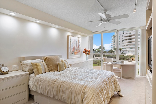 bedroom with ceiling fan, light carpet, rail lighting, and a textured ceiling