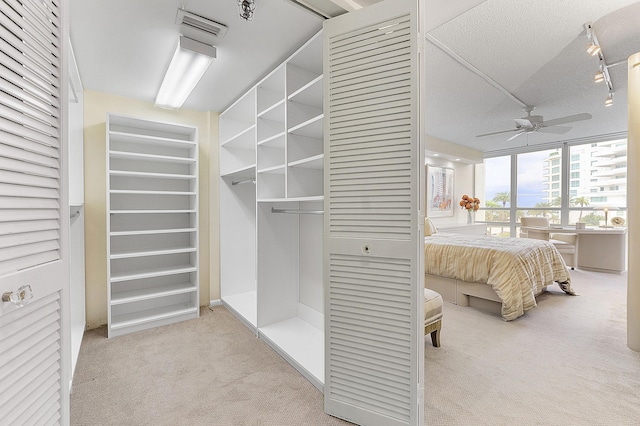 bedroom with visible vents, light colored carpet, a textured ceiling, and rail lighting