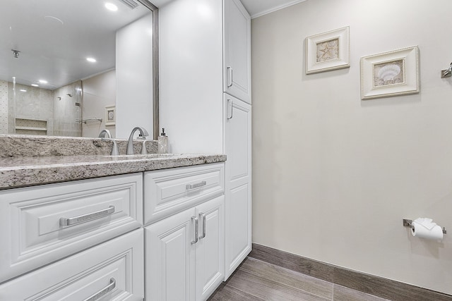 full bathroom featuring recessed lighting, vanity, wood finished floors, tiled shower, and baseboards