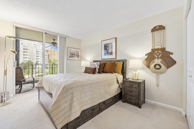 bedroom with baseboards, light colored carpet, access to outside, expansive windows, and a textured ceiling