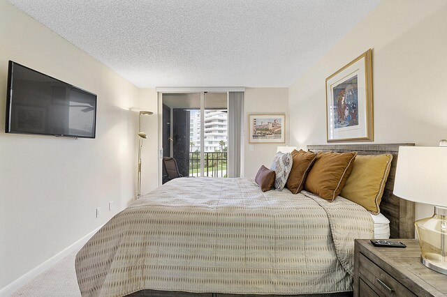 bedroom with access to outside, a textured ceiling, and carpet flooring