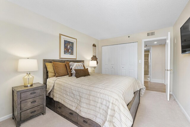 carpeted bedroom featuring a textured ceiling and a closet