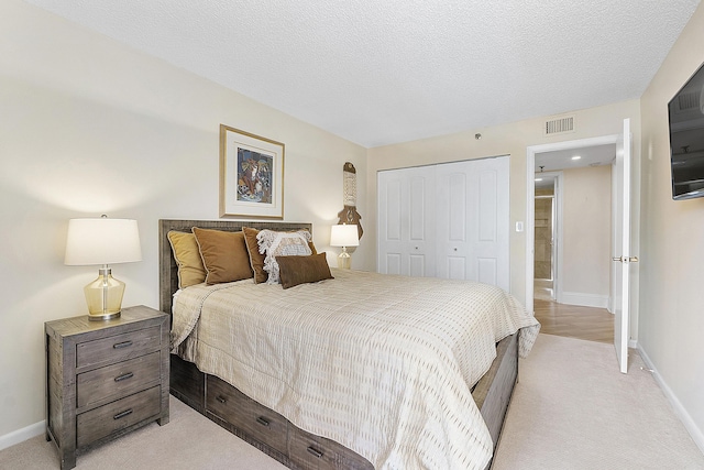 bedroom with a textured ceiling, a closet, visible vents, and baseboards