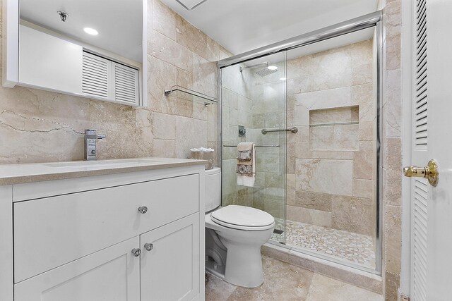 bathroom featuring toilet, a shower stall, tile walls, and vanity