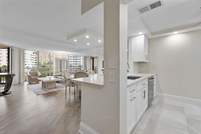 kitchen featuring visible vents, dishwasher, open floor plan, light countertops, and white cabinetry