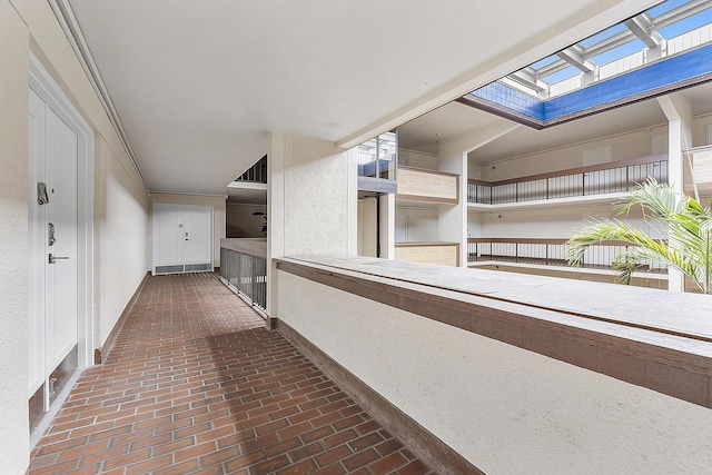 corridor featuring brick floor, a skylight, and baseboards