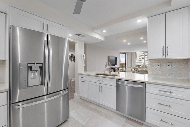 kitchen featuring sink, appliances with stainless steel finishes, decorative backsplash, and white cabinetry