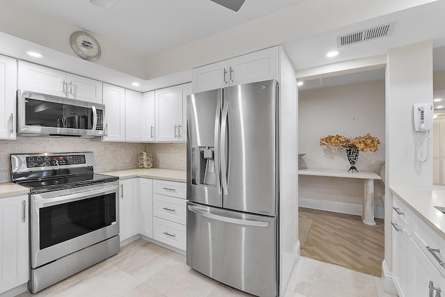 kitchen featuring stainless steel appliances, white cabinets, light countertops, and visible vents